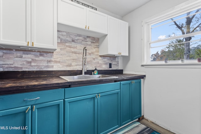 kitchen with backsplash, sink, blue cabinetry, hardwood / wood-style floors, and white cabinetry