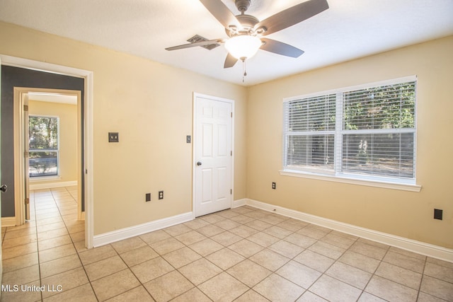 tiled empty room featuring a wealth of natural light and ceiling fan