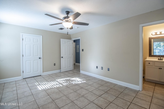 unfurnished bedroom with connected bathroom, ceiling fan, sink, and light tile patterned floors