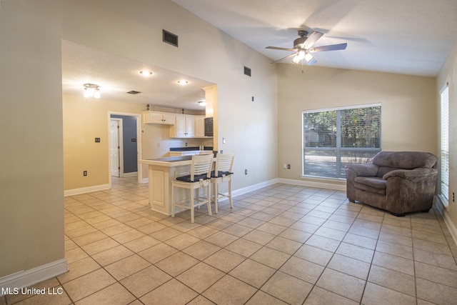 kitchen featuring a breakfast bar, light tile patterned floors, vaulted ceiling, and ceiling fan