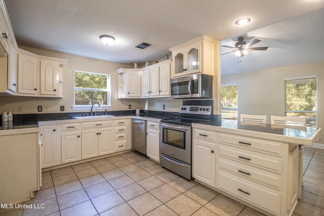 kitchen featuring a textured ceiling, sink, kitchen peninsula, and stainless steel appliances