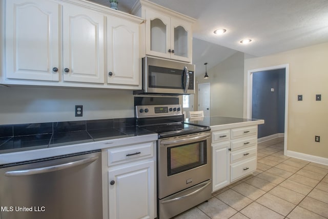 kitchen featuring light tile patterned floors, white cabinetry, appliances with stainless steel finishes, and vaulted ceiling