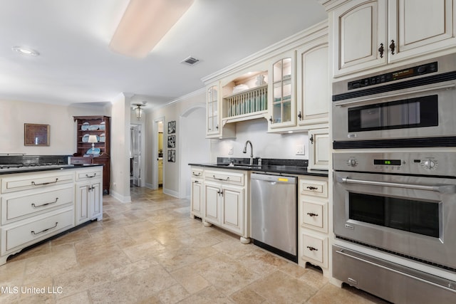 kitchen featuring crown molding, appliances with stainless steel finishes, sink, and cream cabinetry