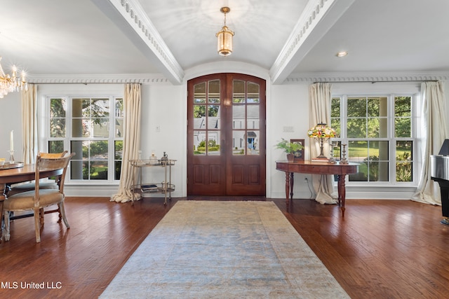 foyer with an inviting chandelier, crown molding, dark hardwood / wood-style floors, and french doors