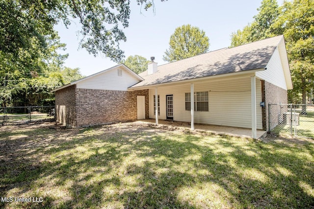 rear view of property featuring a gate, fence, a chimney, a lawn, and brick siding