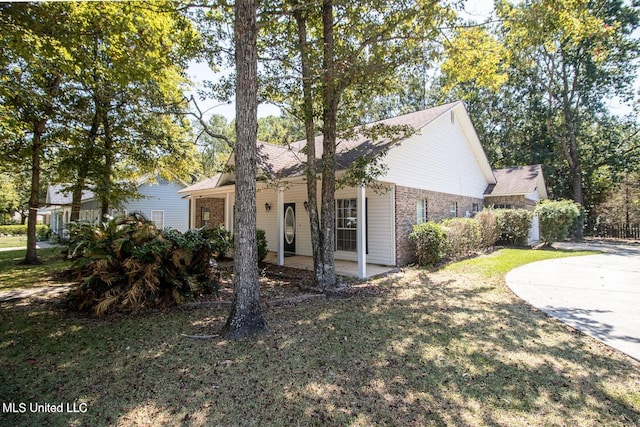 view of front of property with a patio area, brick siding, and a front yard