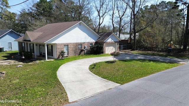 view of front of property with a front yard, fence, brick siding, and curved driveway