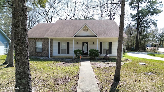 view of front of property featuring a front yard, brick siding, covered porch, and roof with shingles