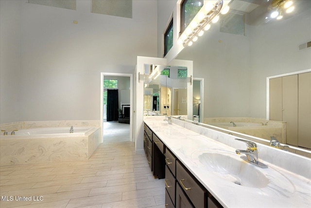 6821 Autumn Oaks Dr, Olive Branch, MS 38654 - bathroom featuring a high ceiling, a garden tub, double vanity, and wood finished floors