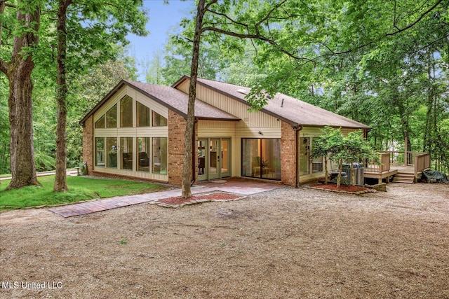 6821 Autumn Oaks Dr, Olive Branch, MS 38654 - back of house with a wooden deck, roof with shingles, a sunroom, and a lawn