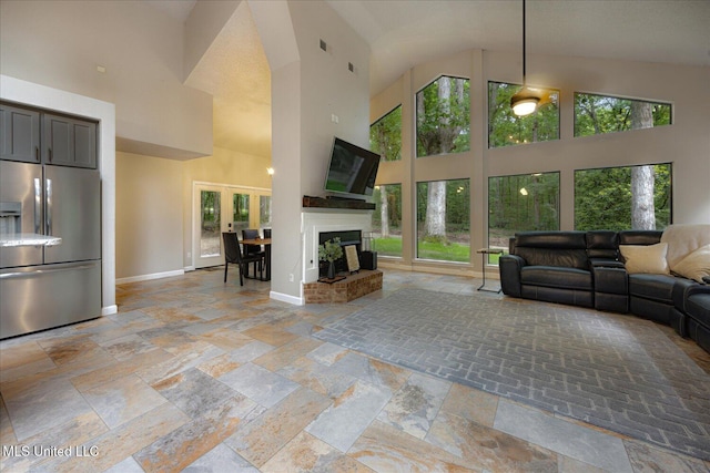 6821 Autumn Oaks Dr, Olive Branch, MS 38654 - living room featuring plenty of natural light, a high ceiling, stone tile flooring, a fireplace with raised hearth, and baseboards