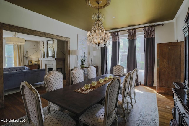 307 Grand Blvd, Greenwood, MS 38930 - dining space with a fireplace, wood finished floors, a chandelier, and a wealth of natural light