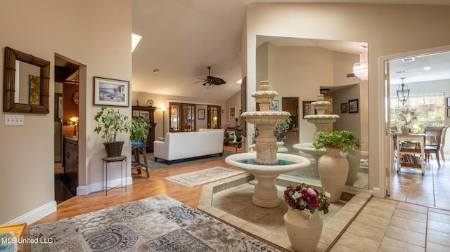 living room with high vaulted ceiling, light tile patterned floors, and ceiling fan with notable chandelier