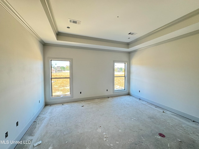 empty room featuring a tray ceiling, a wealth of natural light, and visible vents