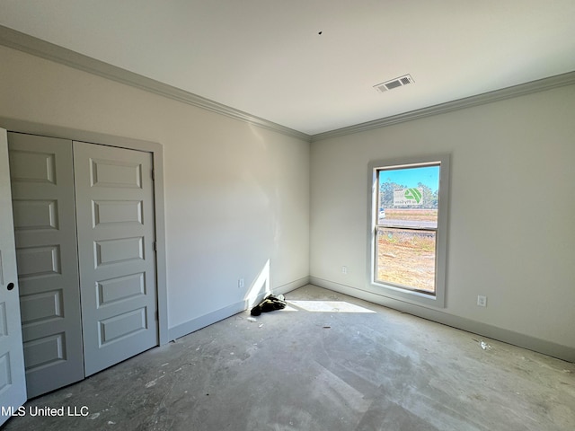 spare room featuring concrete flooring, ornamental molding, visible vents, and baseboards