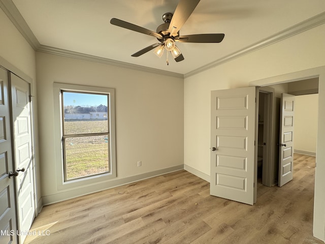 spare room featuring ornamental molding, baseboards, and light wood finished floors