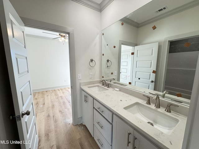 bathroom with visible vents, wood finished floors, a sink, and ornamental molding