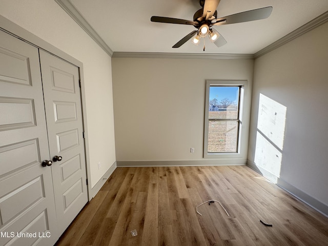 empty room with ornamental molding, ceiling fan, baseboards, and wood finished floors