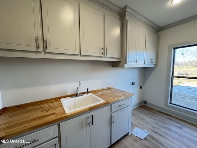 washroom with hookup for a washing machine, hookup for an electric dryer, wood finished floors, a sink, and cabinet space