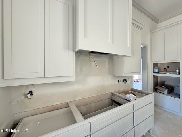 kitchen featuring concrete flooring, light countertops, white cabinets, and ornamental molding