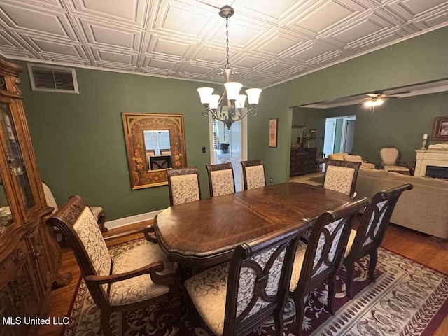 dining room with an ornate ceiling, visible vents, wood finished floors, and ceiling fan with notable chandelier
