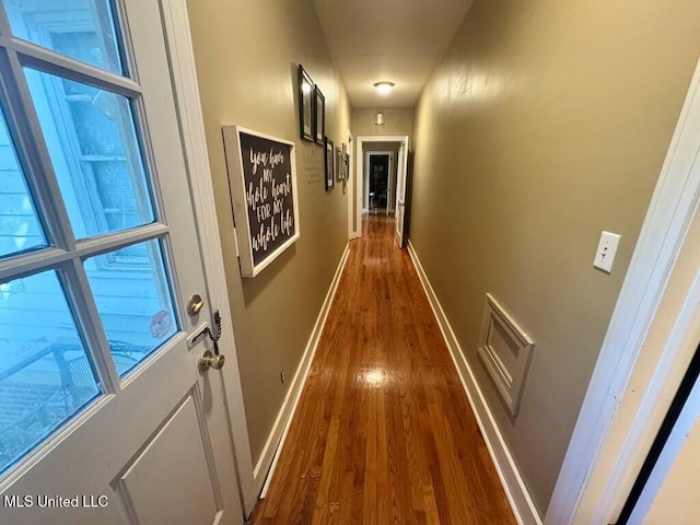 hallway featuring dark wood finished floors, baseboards, and visible vents
