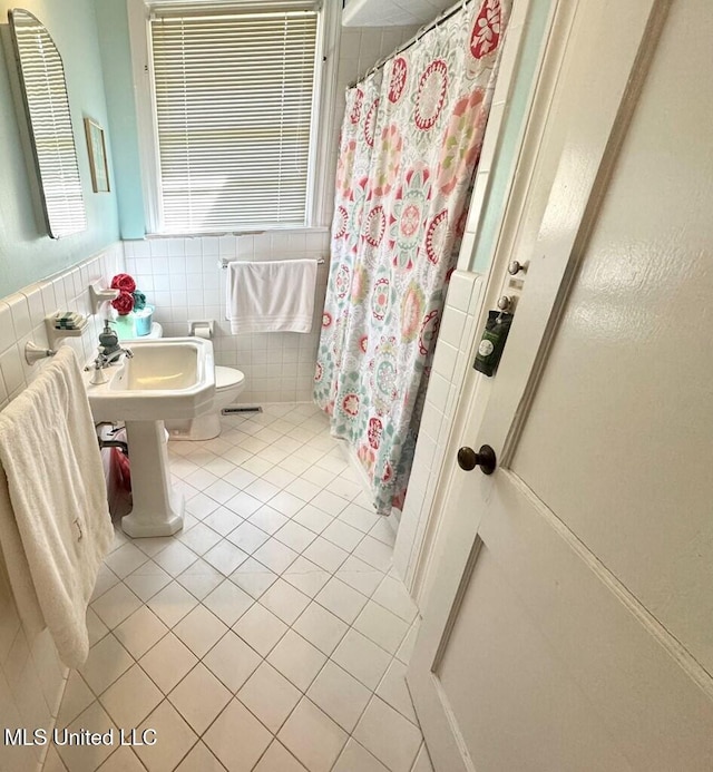 bathroom featuring a shower with curtain, tile patterned floors, toilet, and tile walls