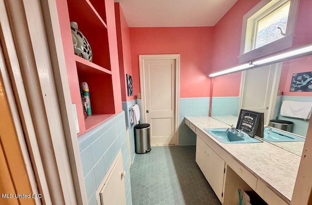 laundry room with tile walls, wainscoting, dark tile patterned flooring, and a sink