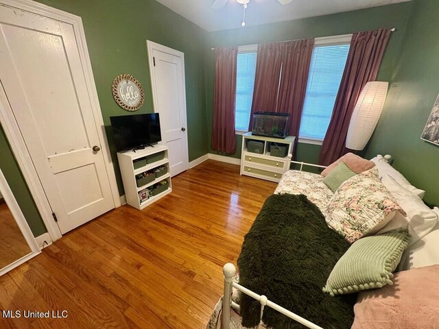 living area with baseboards, wood finished floors, and a ceiling fan