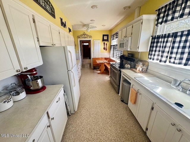 kitchen with a ceiling fan, light countertops, stainless steel appliances, and white cabinetry