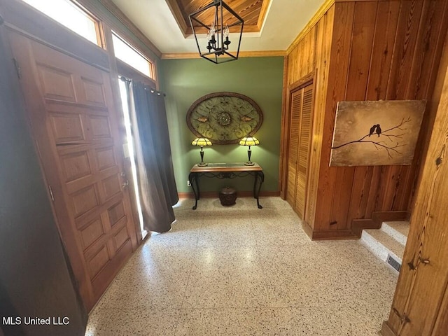 entryway featuring speckled floor, wooden walls, a chandelier, and visible vents
