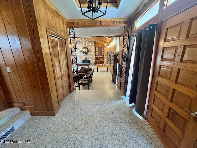 hall featuring speckled floor, a notable chandelier, visible vents, and wood walls