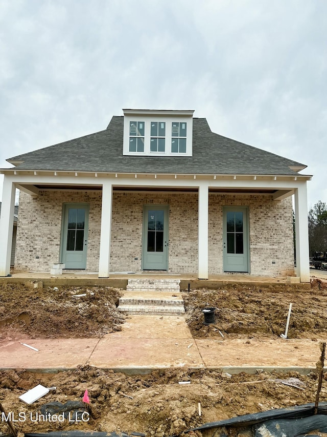 rear view of property with covered porch, brick siding, and a shingled roof