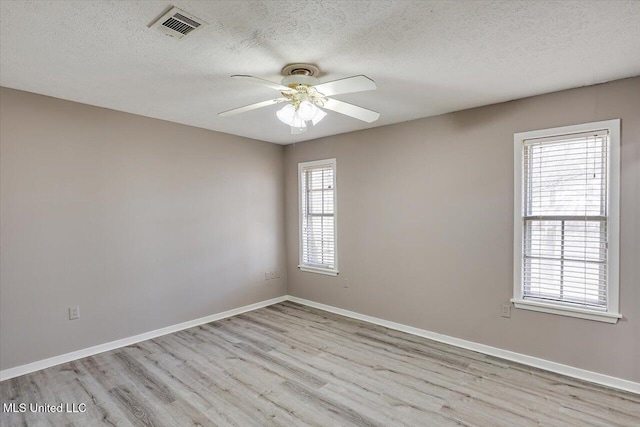 empty room featuring visible vents, baseboards, wood finished floors, a textured ceiling, and a ceiling fan