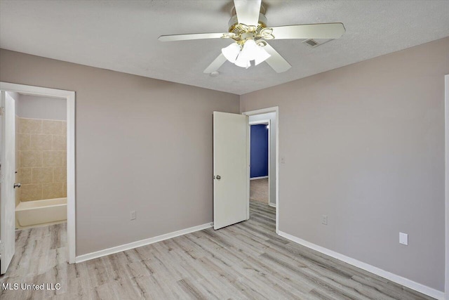 unfurnished bedroom with ceiling fan, baseboards, wood finished floors, ensuite bath, and a textured ceiling