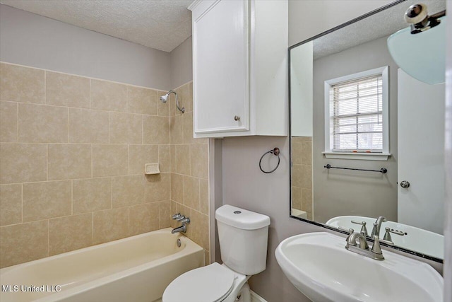 bathroom with a sink, a textured ceiling, shower / tub combination, and toilet