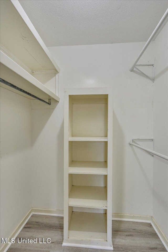 walk in closet with wood finished floors