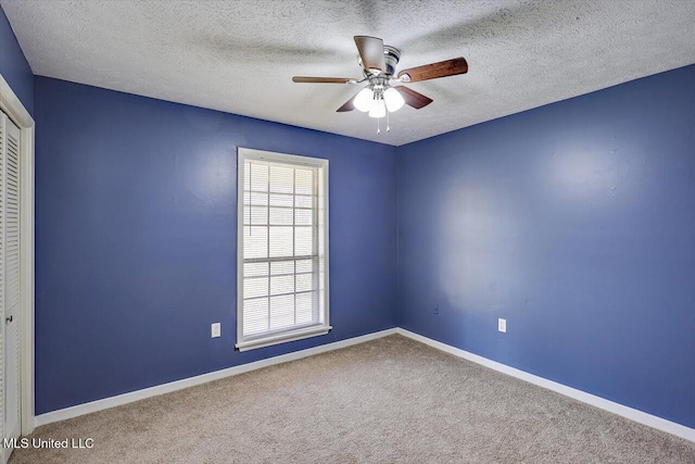 empty room with carpet flooring, ceiling fan, a textured ceiling, and baseboards