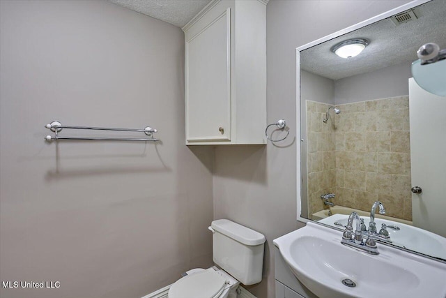 bathroom featuring visible vents, a textured ceiling, vanity, and toilet