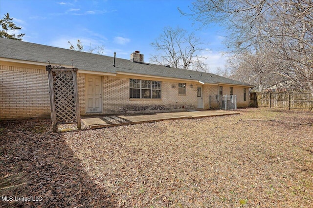 back of property with a patio area, brick siding, a chimney, and fence