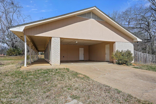 view of front of property featuring brick siding, driveway, and fence