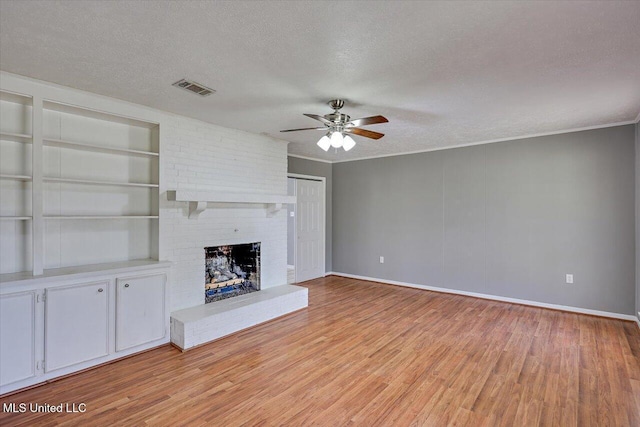 unfurnished living room featuring built in features, visible vents, a textured ceiling, and a fireplace