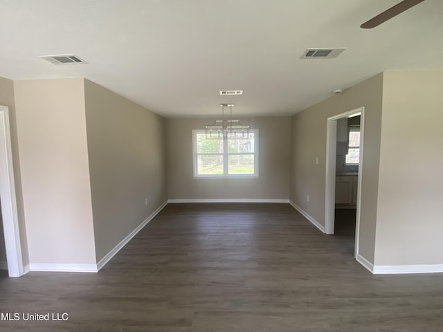 unfurnished dining area with dark wood-style floors, visible vents, and baseboards