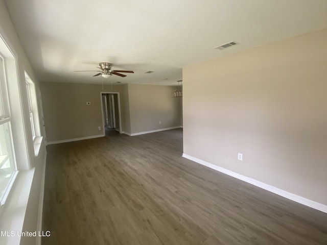 unfurnished room featuring dark wood-type flooring, visible vents, baseboards, and ceiling fan