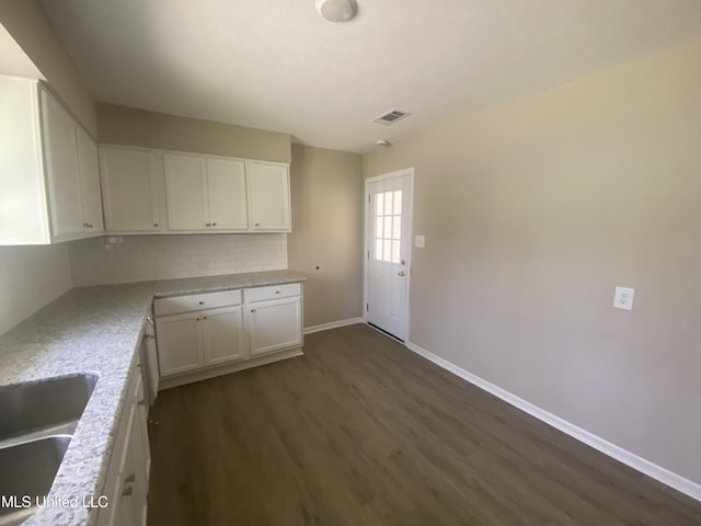 kitchen with tasteful backsplash, visible vents, white cabinets, and dark wood-style flooring