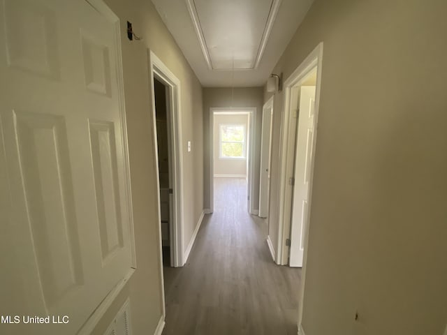 hallway with baseboards, attic access, and wood finished floors