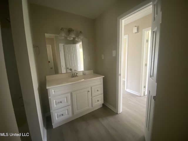 bathroom featuring baseboards, wood finished floors, and vanity