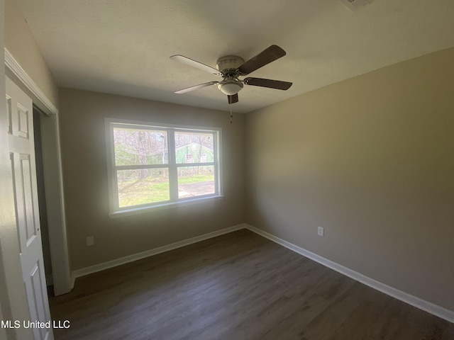 unfurnished bedroom with a closet, ceiling fan, baseboards, and dark wood-style flooring