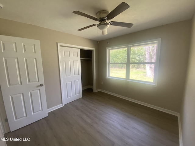 unfurnished bedroom with a ceiling fan, baseboards, dark wood-style flooring, and a closet