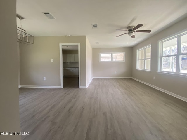 empty room with visible vents, baseboards, wood finished floors, and a ceiling fan